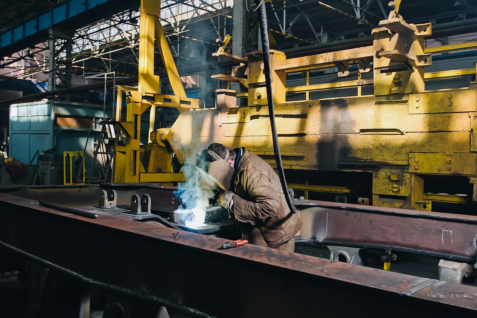 Train manufactory with welder during work on iron spare parts Train manufactory with welder during work on iron spare parts