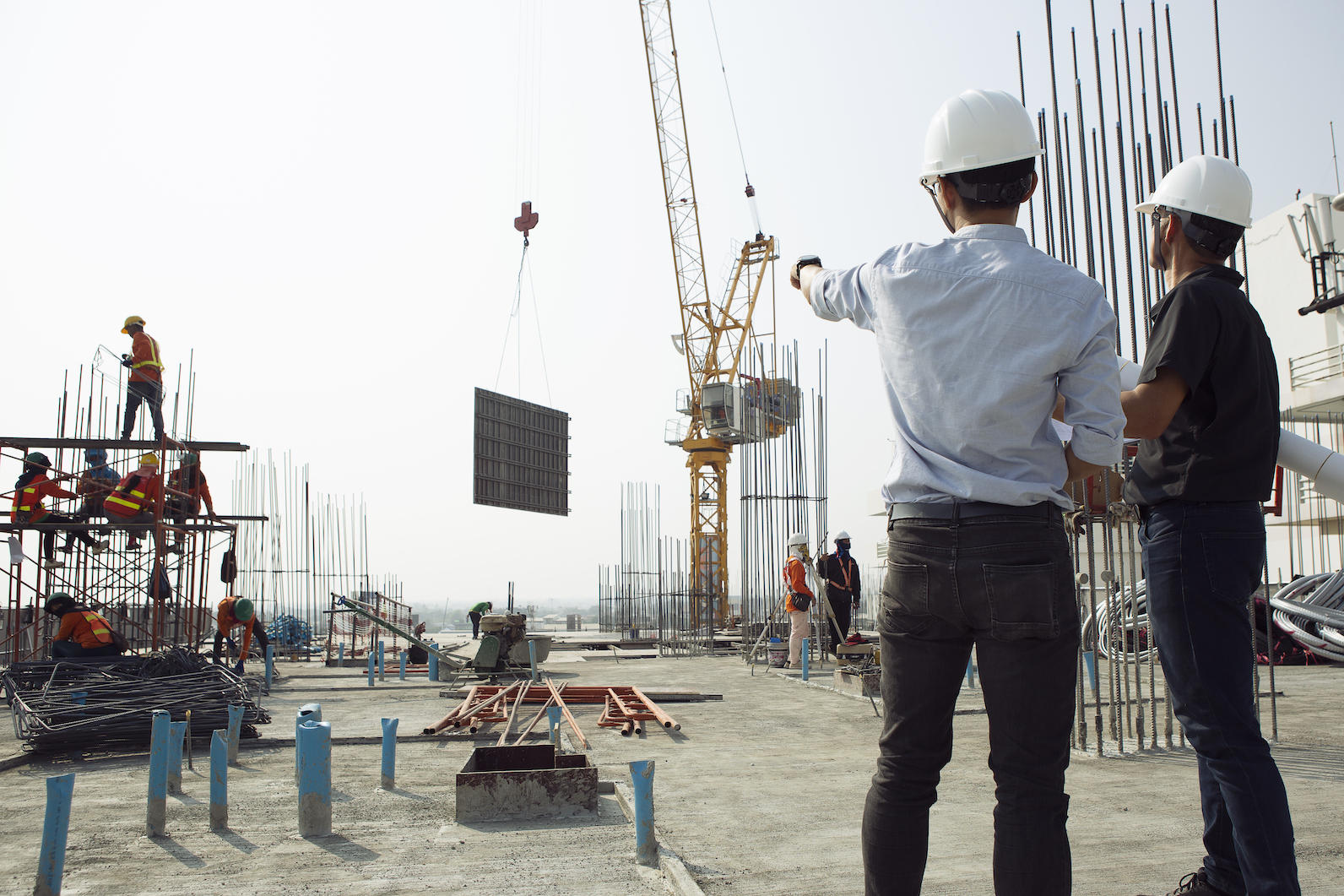 Two engineers work on the construction site. They are checking the progress of the work.